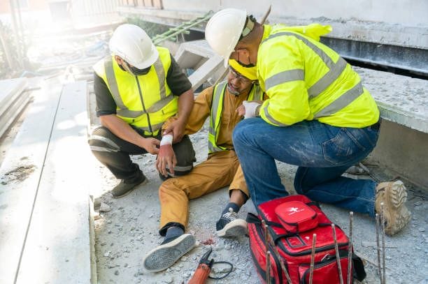 Two construction workers helping their team member after he had a common workplace accident.