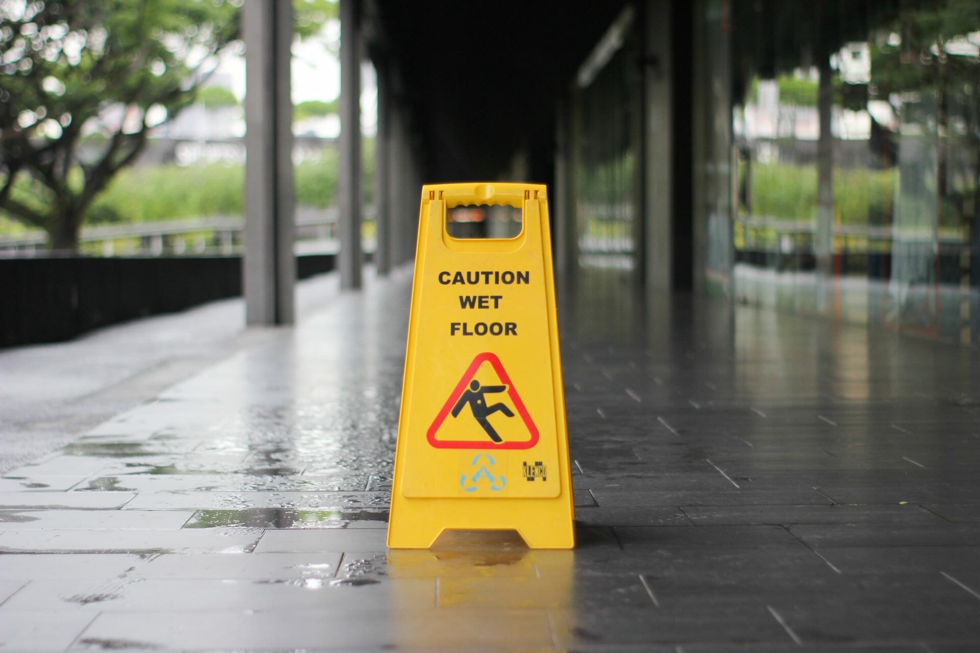 A wet floor sign on an uneven wet surface outside of a building to help prevent common slip and fall accidents.